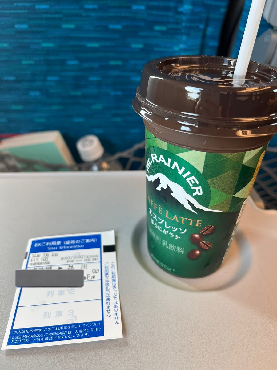 新幹線の座席のテーブルに置いた飲み物と座席の案内票